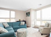 Thumbnail 43 of 72 - A living room with a blue couch and a patterned ottoman.