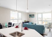 Thumbnail 68 of 72 - A kitchen with a white counter top and a blue couch in the background.