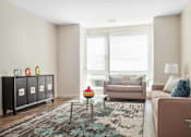 Thumbnail 42 of 72 - A living room with a couch, a chair, a table, and a rug.