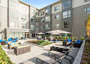 Thumbnail 30 of 72 - A sunny day at a modern apartment complex with a well-kept courtyard.