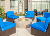 Thumbnail 31 of 72 - A patio with blue chairs and a fire pit.