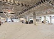Thumbnail 71 of 72 - A spacious parking garage with concrete floors and multiple cars parked.