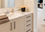 Thumbnail 14 of 24 - A bathroom with a sink, mirror, and cabinets.