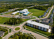 Thumbnail 18 of 24 - An aerial view of a roundabout with a building complex and a parking lot.