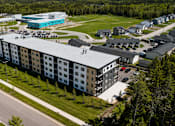 Thumbnail 20 of 24 - A large building with a blue section on the side is surrounded by trees and other buildings.