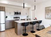 Thumbnail 21 of 24 - A modern kitchen with a wooden island and black barstools.
