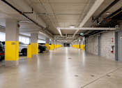 Thumbnail 8 of 24 - A parking garage with yellow poles and a fire extinguisher on the wall.