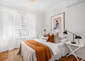 Thumbnail 4 of 12 - a bedroom with white walls and a bed with white and orange pillows
