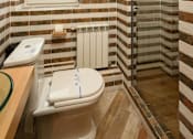 Thumbnail 2 of 15 - A bathroom with a toilet, tiled walls, and a window.
