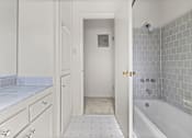 Thumbnail 12 of 12 - A white bathroom with a tiled floor and a white bathtub.