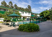 Thumbnail 7 of 12 - A green umbrella is in front of a white building.