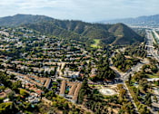 Thumbnail 3 of 12 - A cityscape with a mix of residential and commercial buildings, surrounded by hills and a highway.