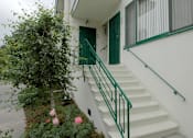 Thumbnail 8 of 12 - A white house with a green door and staircase.
