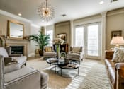 Thumbnail 17 of 21 - A living room with a grey couch, a coffee table, a fireplace, and a chandelier.