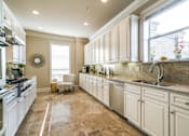 Thumbnail 19 of 21 - A kitchen with white cabinets and a tiled floor.