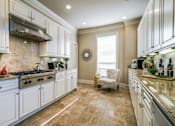 Thumbnail 14 of 21 - A kitchen with white cabinets and a beige floor.