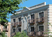 Thumbnail 2 of 21 - A building with a balcony and a tree in front of it.