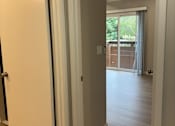 Thumbnail 32 of 41 - A white door is open to a room with wooden floors.