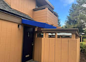 Thumbnail 38 of 41 - A small building with a brown door and a blue awning.