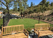 Thumbnail 21 of 31 - a backyard with two wooden benches and a chain link fence