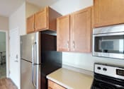 Thumbnail 5 of 25 - A kitchen with a black refrigerator and wooden cabinets.