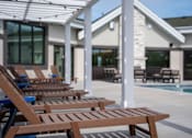 Thumbnail 22 of 34 - A row of wooden lounge chairs are arranged on a patio.
