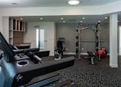 Thumbnail 18 of 34 - A gym with a treadmill, weights, and a ball.