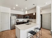 Thumbnail 2 of 33 - A modern kitchen with a white island and black stools.
