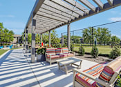 Thumbnail 35 of 46 - A sunny day at the park with a striped couch and a bench under a canopy.