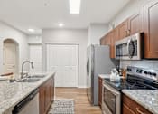 Thumbnail 50 of 53 - A kitchen with a granite countertop and stainless steel appliances.