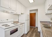 Thumbnail 2 of 24 - A white stove and oven in a kitchen with a brown door.