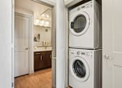 Thumbnail 9 of 33 - A white washing machine is stacked on top of another white washing machine in a laundry room.