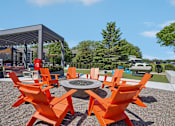 Thumbnail 42 of 46 - A patio with orange chairs and a fire pit.