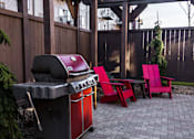 Thumbnail 19 of 25 - A red grill is in the middle of a patio with matching red chairs.