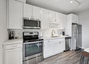 Thumbnail 13 of 49 - A modern kitchen with white cabinets and stainless steel appliances.