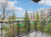 Thumbnail 21 of 45 - A balcony with a black railing overlooks a green lawn and a brick building.