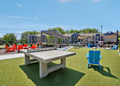 Thumbnail 43 of 46 - A concrete table and chairs are set up on a green lawn.