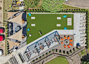 Thumbnail 30 of 46 - An aerial view of a parking lot with cars and a building with a green lawn in front.