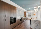 Thumbnail 31 of 45 - A modern kitchen with wooden cabinets and marble countertops.