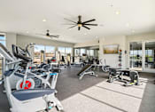 Thumbnail 27 of 40 - A spacious gym with a variety of exercise equipment and a ceiling fan.