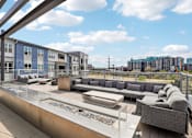Thumbnail 17 of 40 - A modern outdoor seating area with a glass table and grey couches.