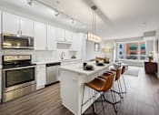 Thumbnail 4 of 49 - A modern kitchen with white cabinets and stainless steel appliances.