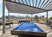 Thumbnail 24 of 40 - A pool table is on a patio with a view of the city.