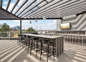 Thumbnail 20 of 40 - A patio with a bar and stools under a corrugated roof.