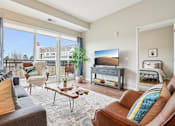 Thumbnail 4 of 42 - A living room with a brown leather couch and a wooden coffee table.