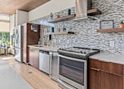 Thumbnail 25 of 33 - a kitchen with stainless steel appliances and a stone wall