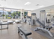 Thumbnail 14 of 33 - a gym with cardio equipment and weights in a building with large windows