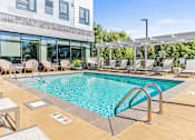 Thumbnail 11 of 33 - a swimming pool with lounge chairs and a building with glass windows