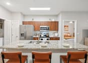 Thumbnail 2 of 54 - A kitchen with a granite countertop and brown chairs.