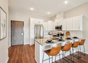Thumbnail 1 of 42 - A kitchen with a white counter top and brown chairs.
